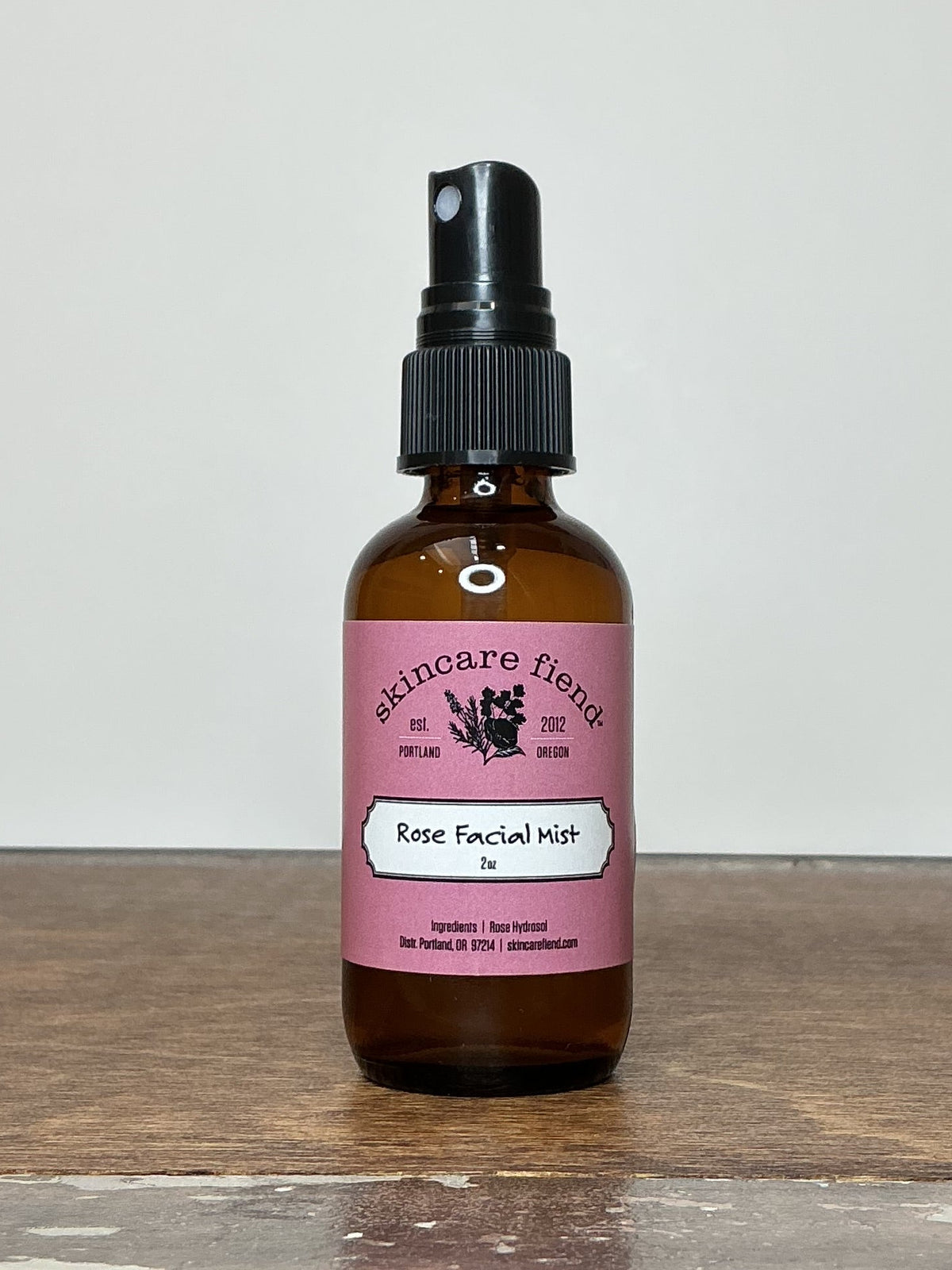 2 ounce bottle of Skincare Fiend Rose Facial Mist on a wooden table.